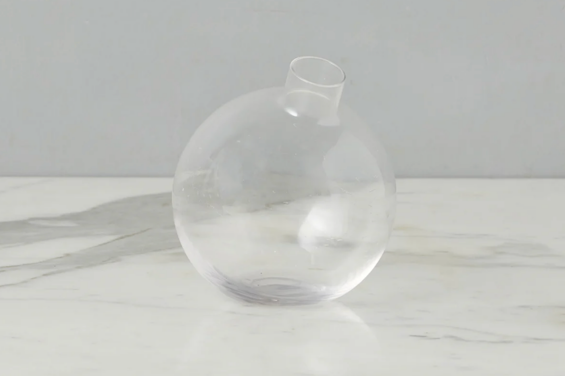 Clear glass vase on a white surface with a light gray background