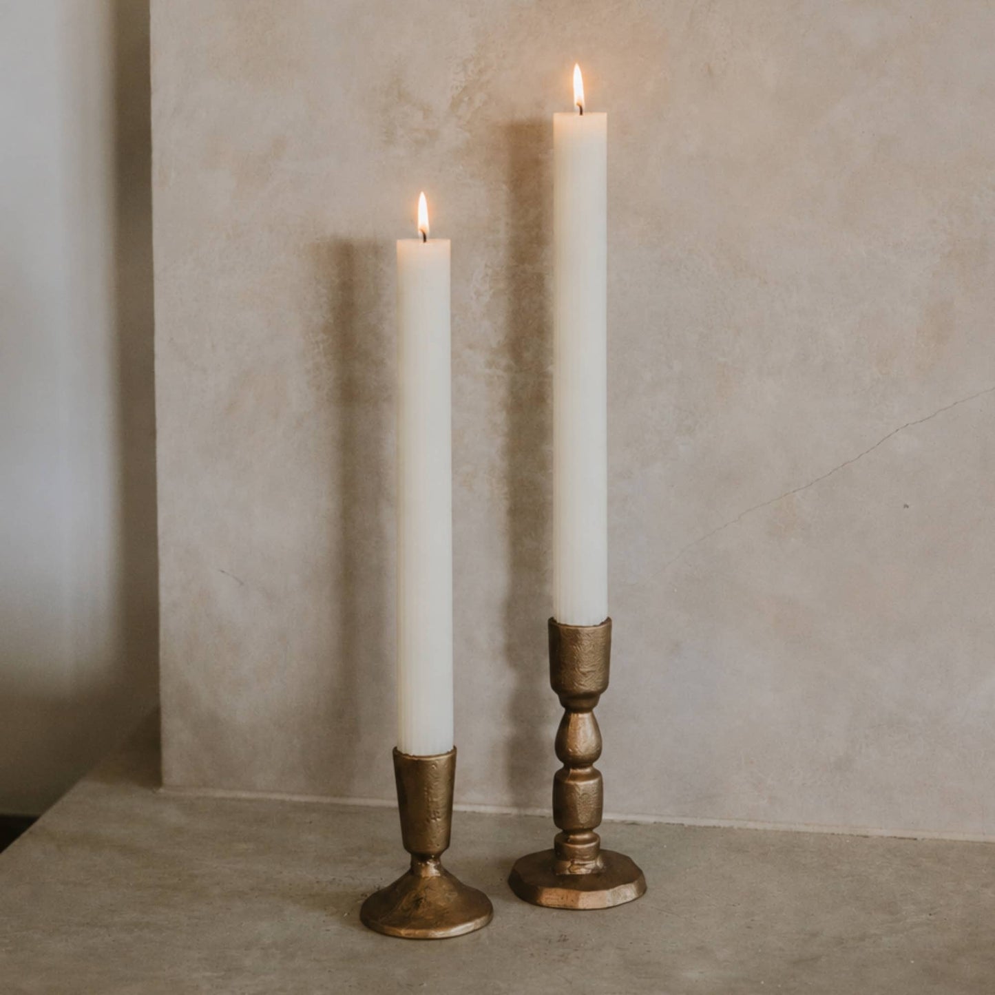 Set of two antique gold cast iron taper candle holders with a timeless candlestick silhouette.