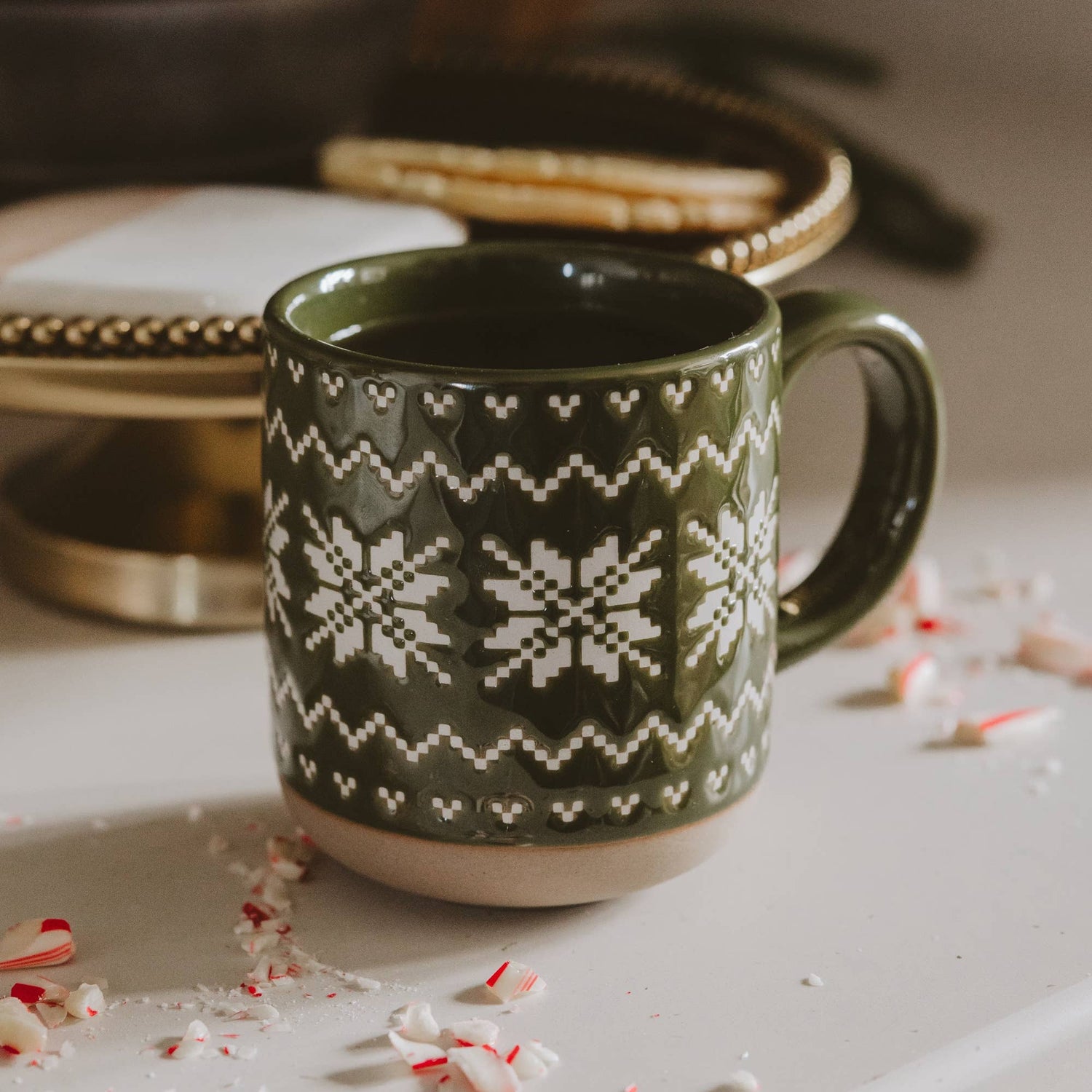 Green stoneware coffee mug featuring an embossed Fair Isle sweater pattern with a speckled finish and exposed natural stoneware base.
