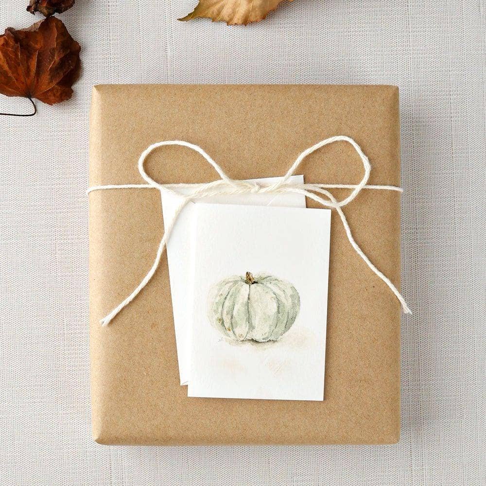 Green pumpkin mini enclosure card tucked into a wrapped hostess gift with kraft paper.