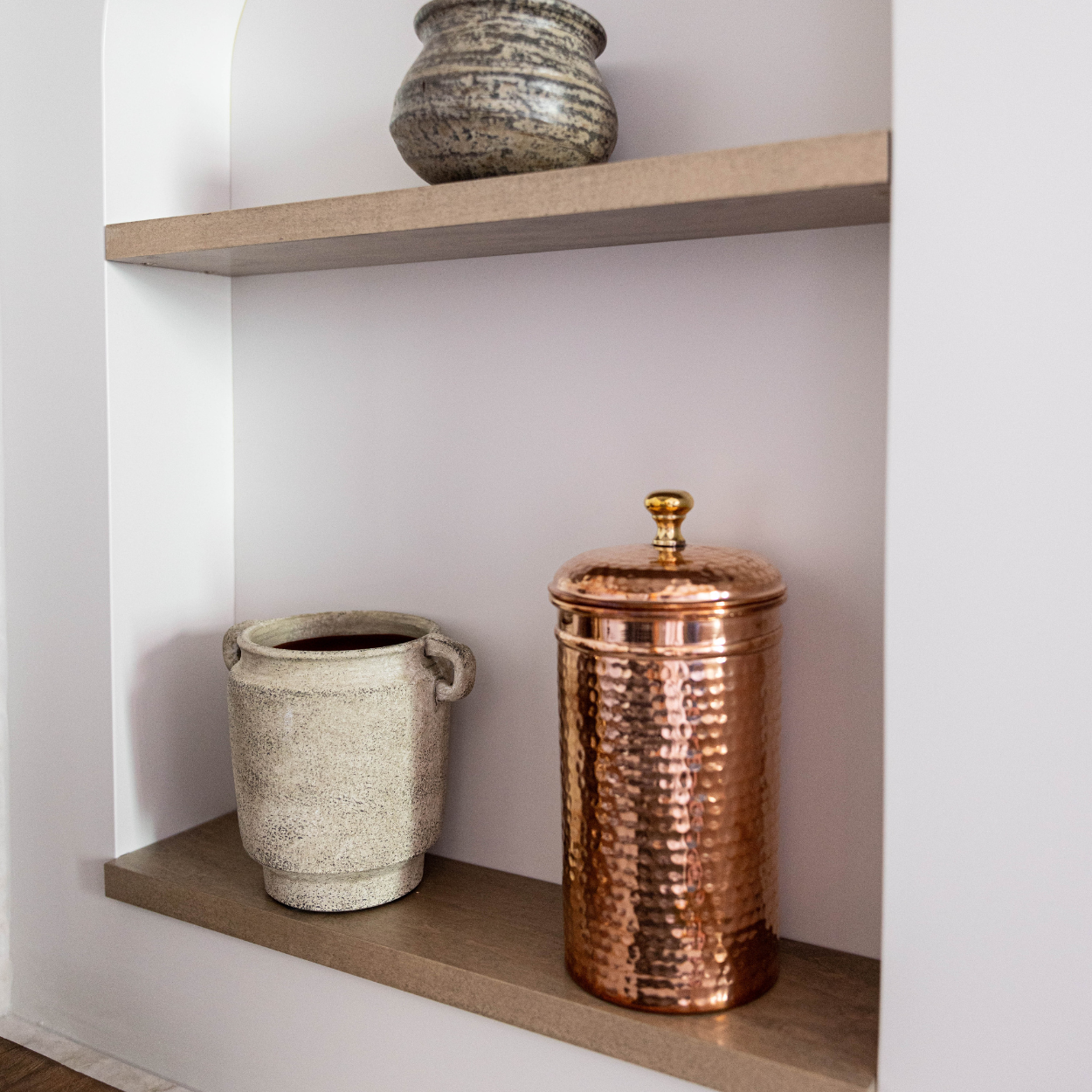 Hammered copper storage canister with fitted lid and warm vintage-inspired finish styled on kitchen counter