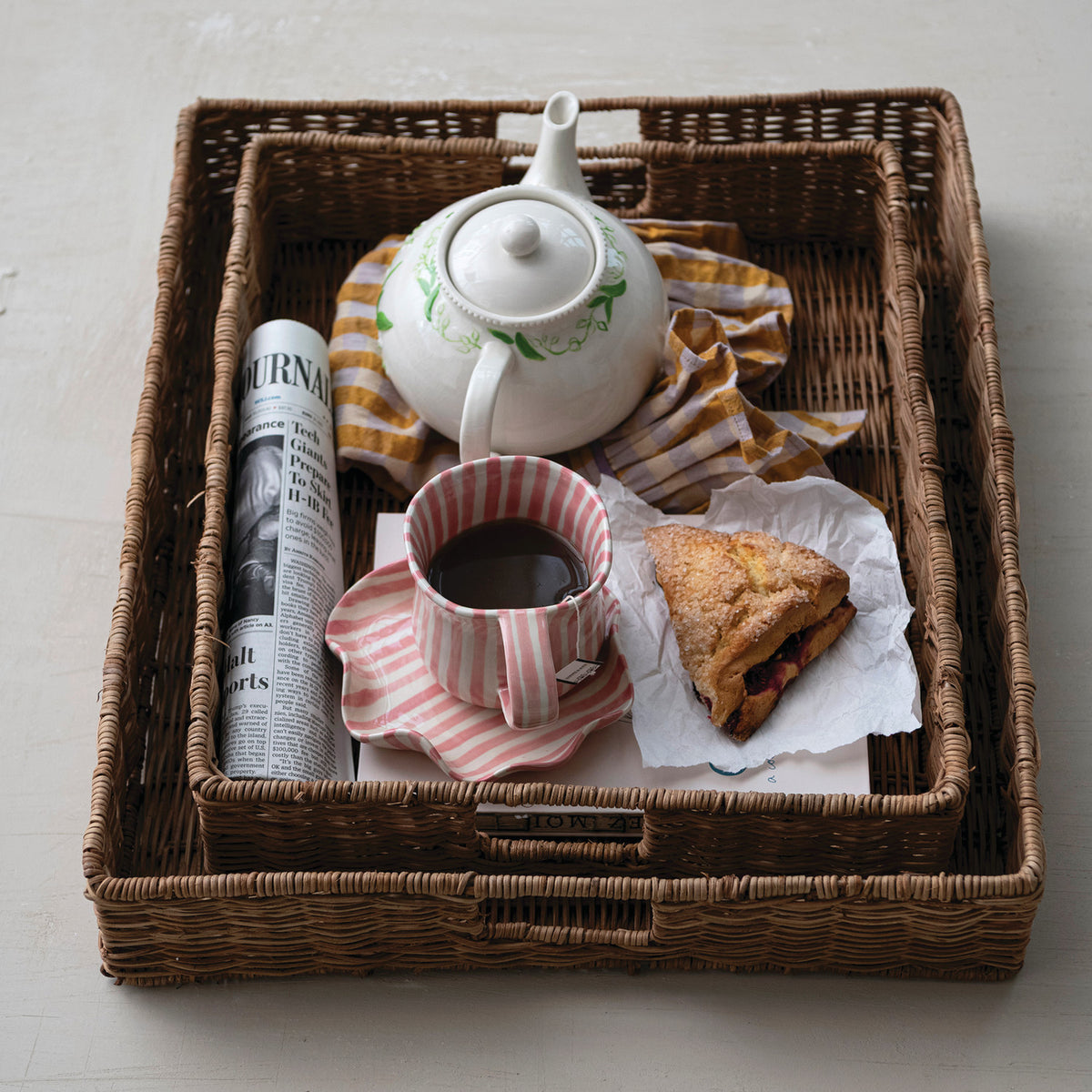 Hand-woven natural rattan tray with integrated metal handles and a warm woven texture.