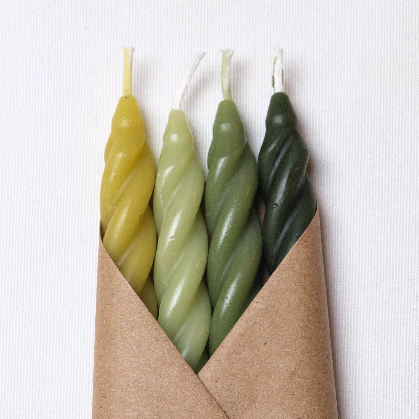 Close-up of the sculptural spiral design showcasing the natural beeswax texture and rich woodland colors.