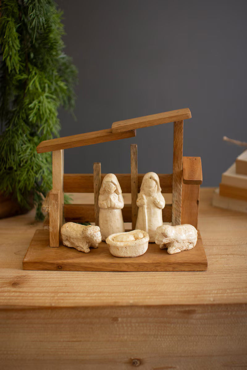 Wooden nativity displayed on a mantel with natural holiday greenery and warm Christmas décor