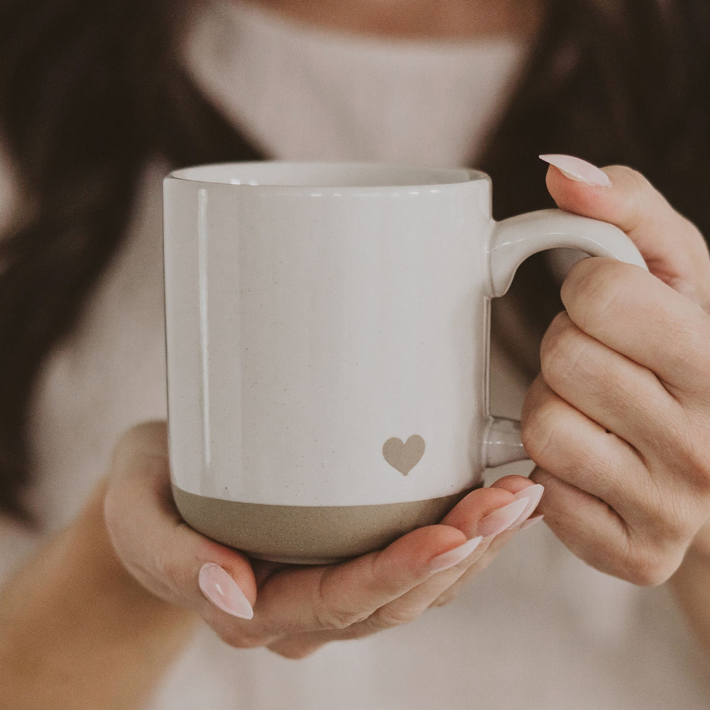 Cream stoneware coffee mug with a natural heart design, speckled glaze, and exposed stoneware base.