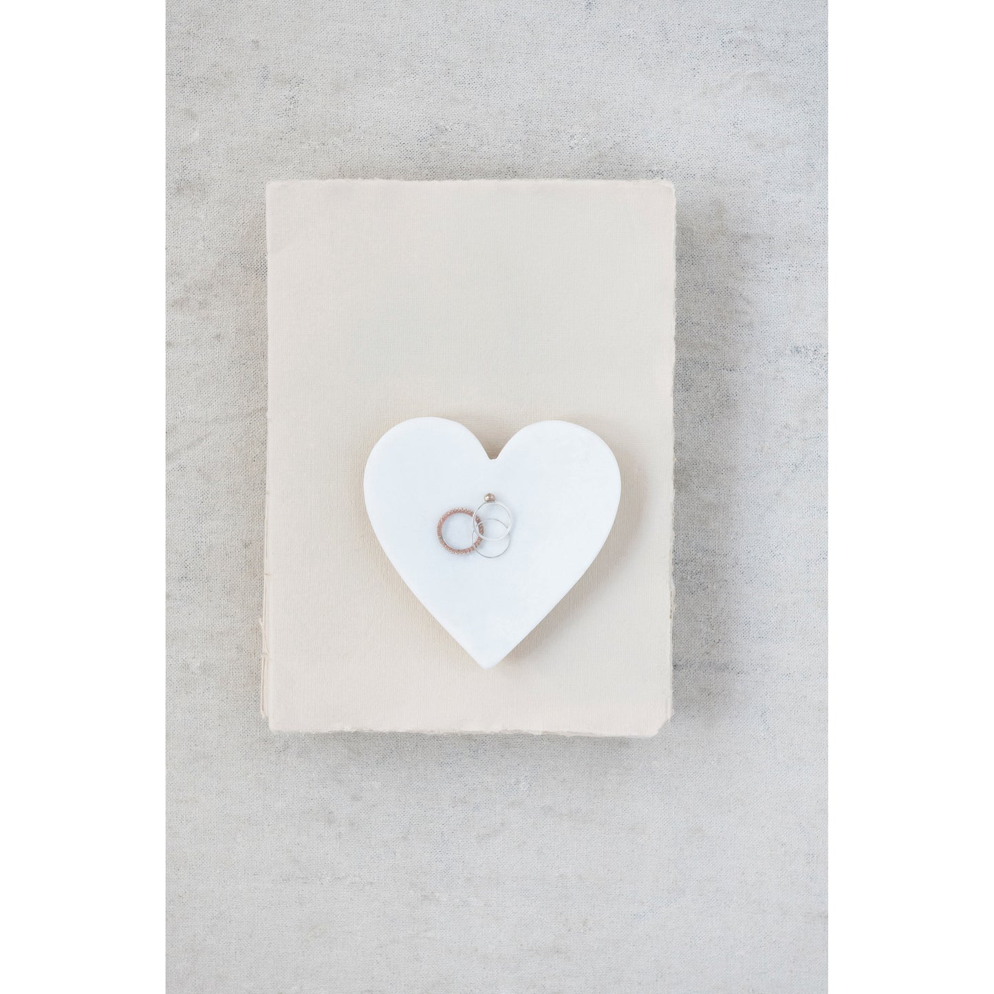 Marble heart dish holding rings and jewelry on a styled vanity.