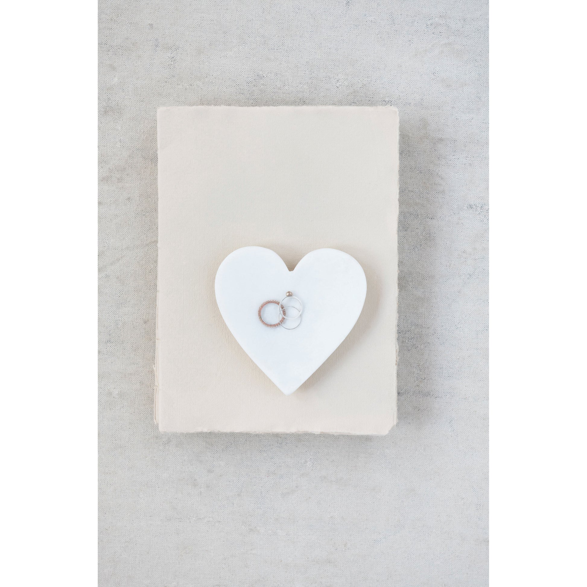 Marble heart dish holding rings and jewelry on a styled vanity.