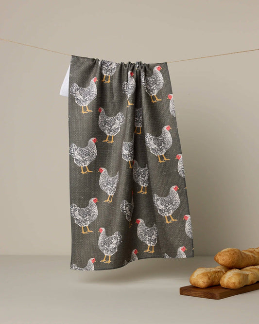 Towel with chicken pattern hanging on a line against a beige background
