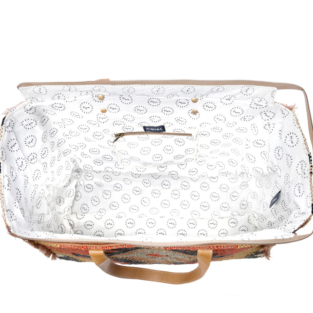 Kaliko Hill Weekender Bag featuring a woven tribal-inspired rug textile, caramel leather straps, and a spacious zip-top design.