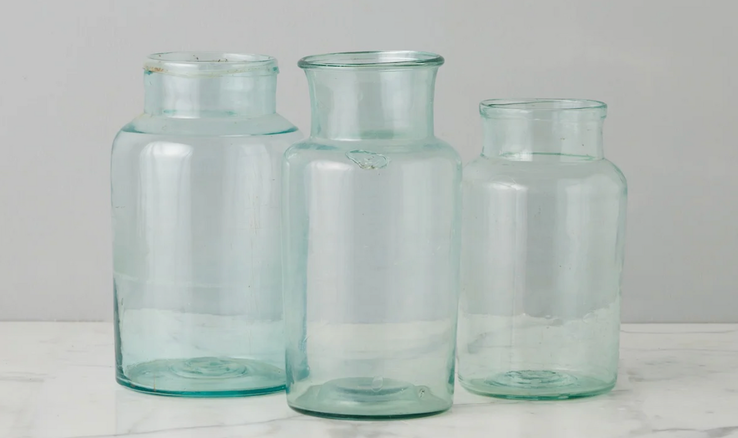 Three clear glass jars of different sizes on a light gray background