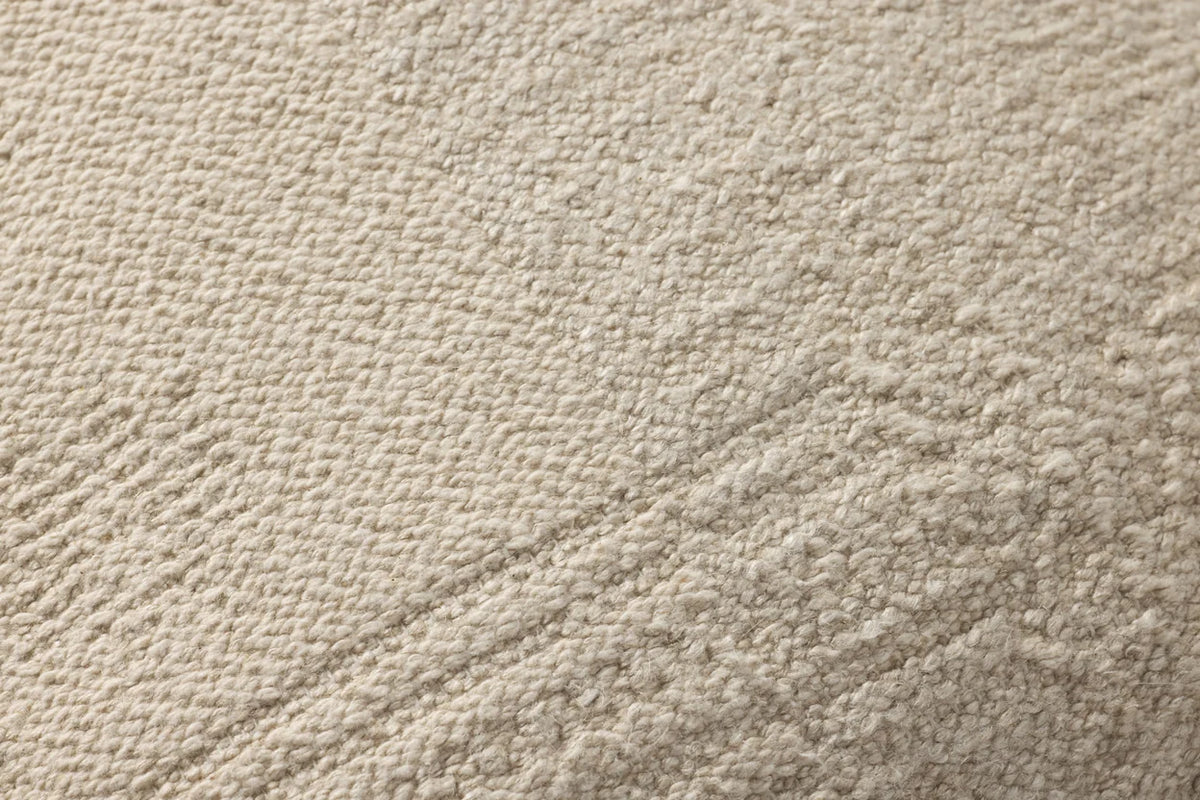 Close-up of the natural textured pillow highlighting the jacquard woven fabric, knife-edge finish, and hidden zipper with antique bronze Loloi logo pull.