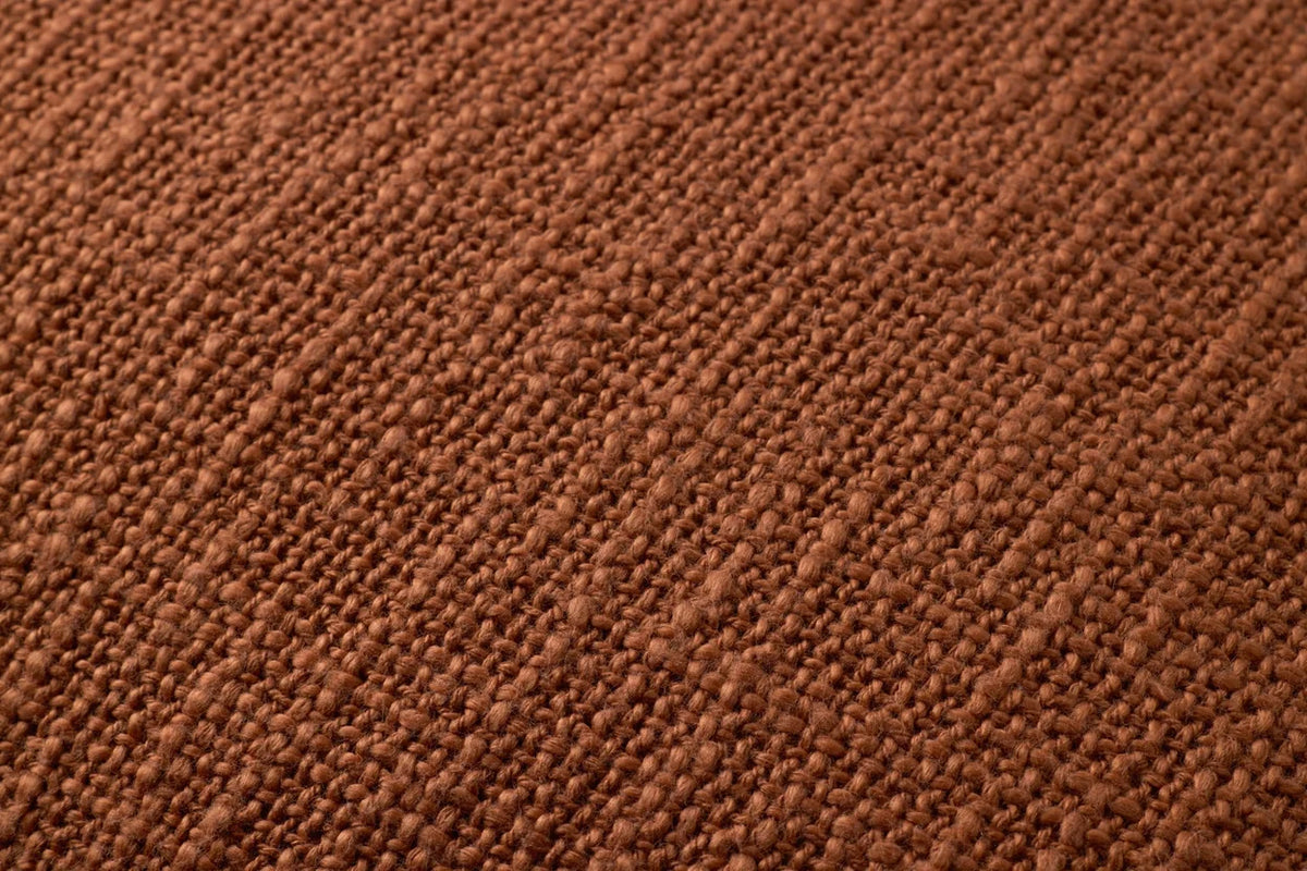 Close-up of the terracotta woven pillow highlighting the textured cotton fabric, white contrast stitching, flange edge, and hidden zipper with antique bronze Loloi logo pull.