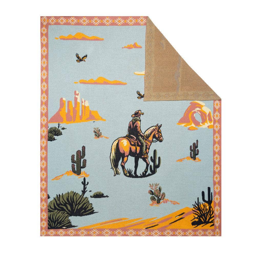 Lone Bronco Rider Woven Throw Blanket featuring a cowboy riding a bucking bronco beneath a dusty blue prairie sky with a tribal-inspired border.