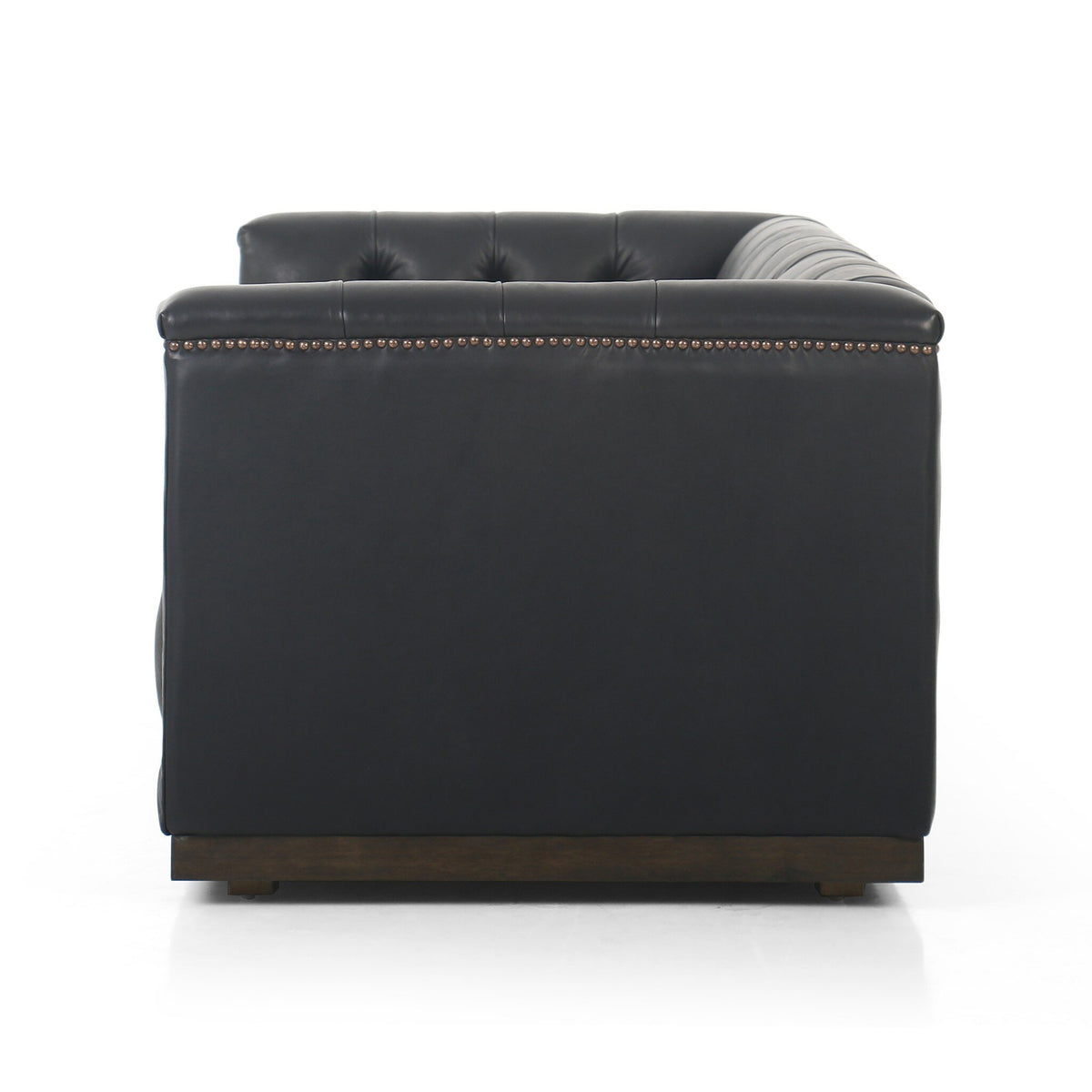 ide view of the Maxx Leather Sofa showing its low profile, structured arms and solid parawood base.