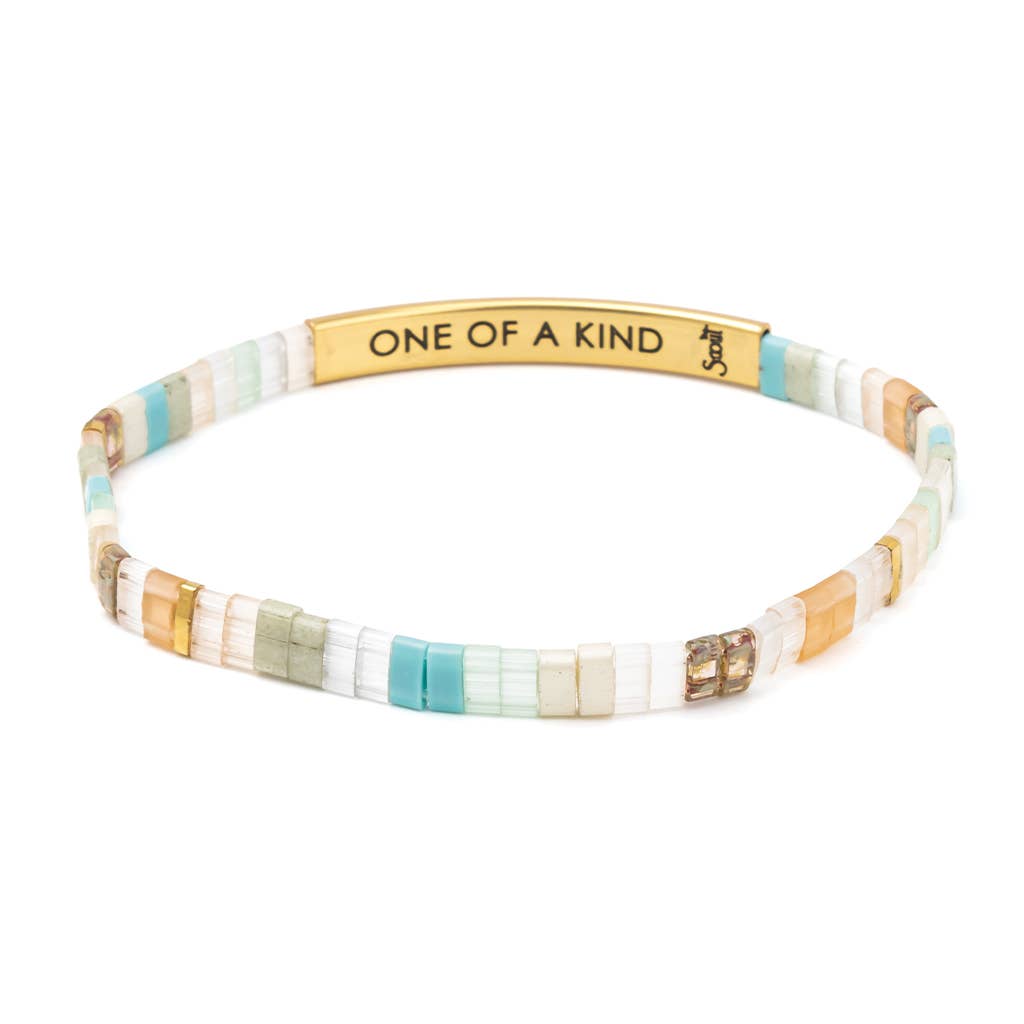 Close-up of mint and peach Miyuki beads, engraved gold bar, and embossed Sparkle & Shine leather hangtag.