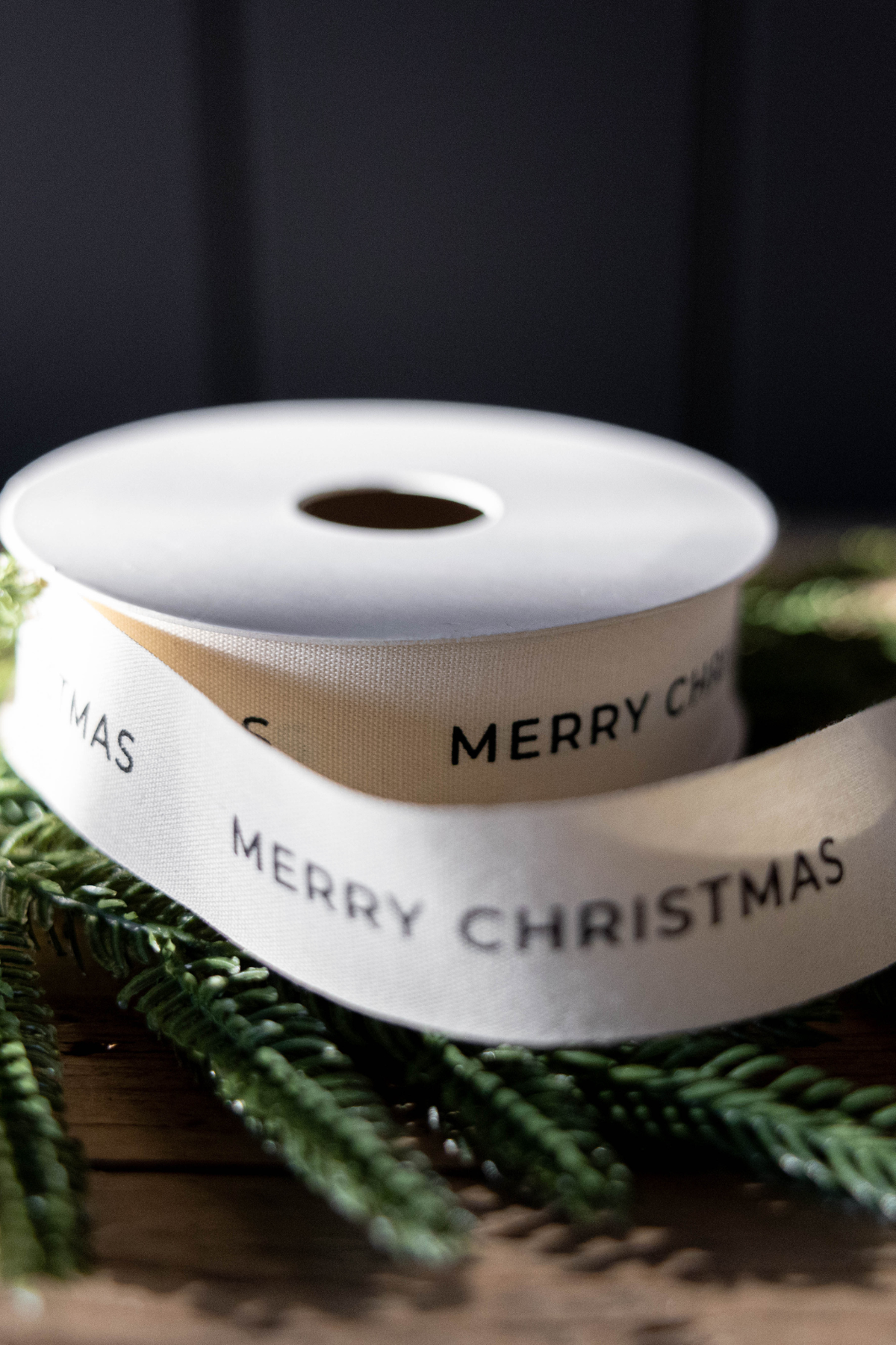 Natural-colored Merry Christmas ribbon with black printed lettering, measuring 1 inch wide.