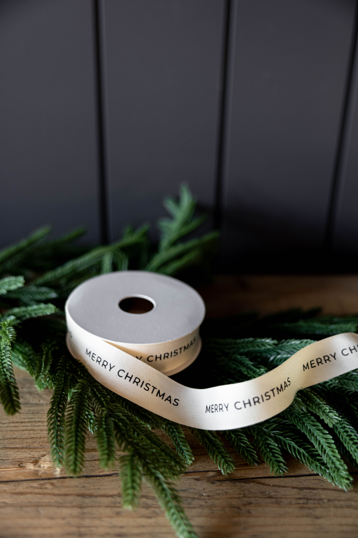 Natural-colored Merry Christmas ribbon with black printed lettering, measuring 1 inch wide.