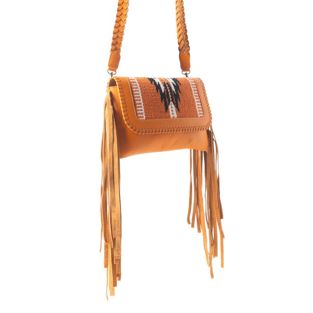 Close-up of the Mesa WingTrail bag showing warm leather, woven textile, decorative whipstitching, and fringe details.