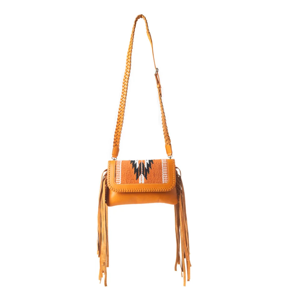 Mesa WingTrail crossbody bag in amber tan leather with a Southwestern woven rug panel, whipstitch detailing, and fringe.