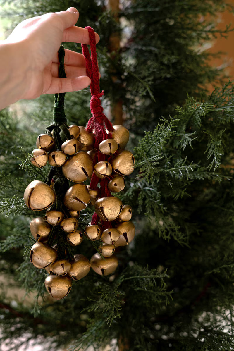 Close-up of antique gold jingle bells gathered with a soft red velvet ribbon.