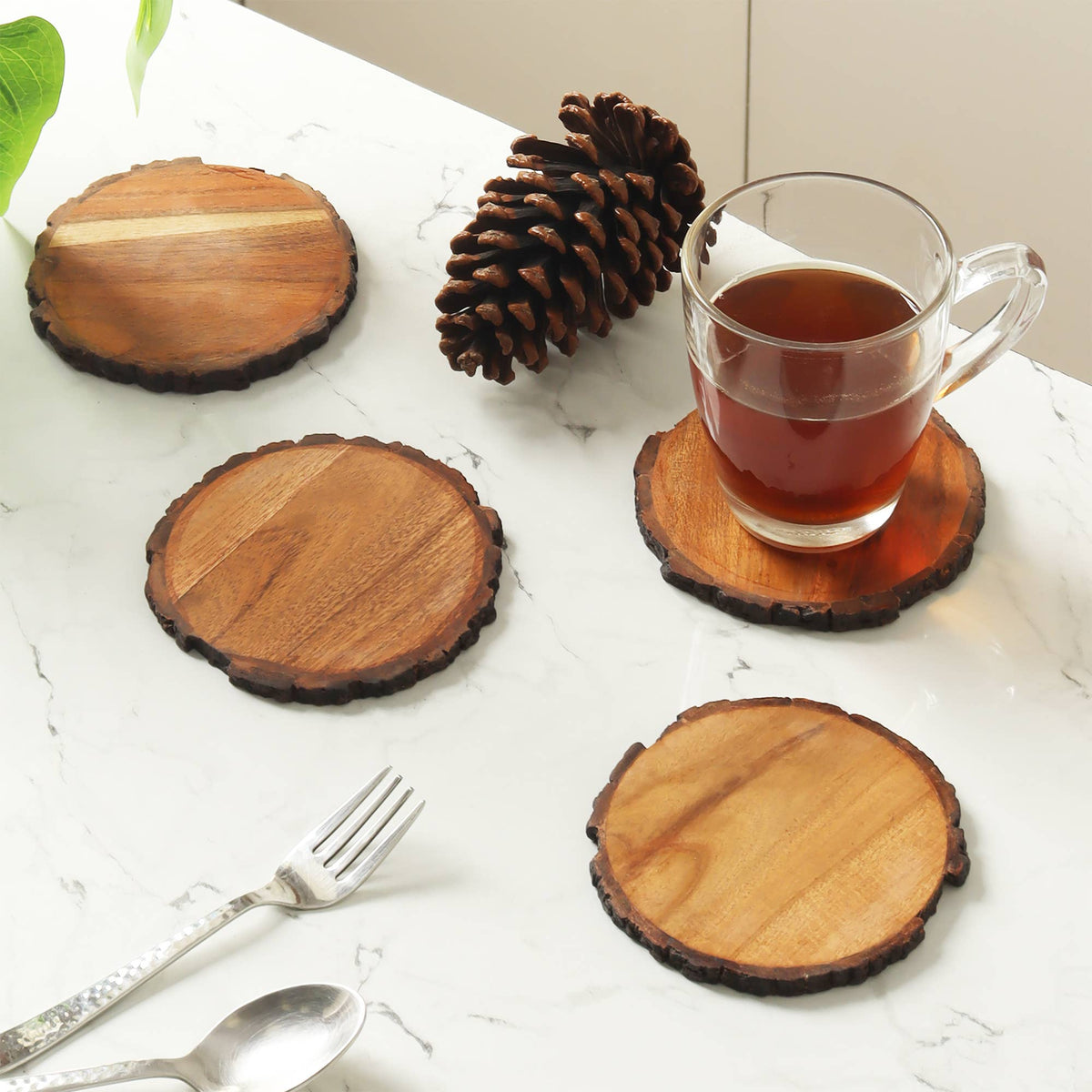 Set of four round natural wood coasters with organic bark edges and visible wood grain.