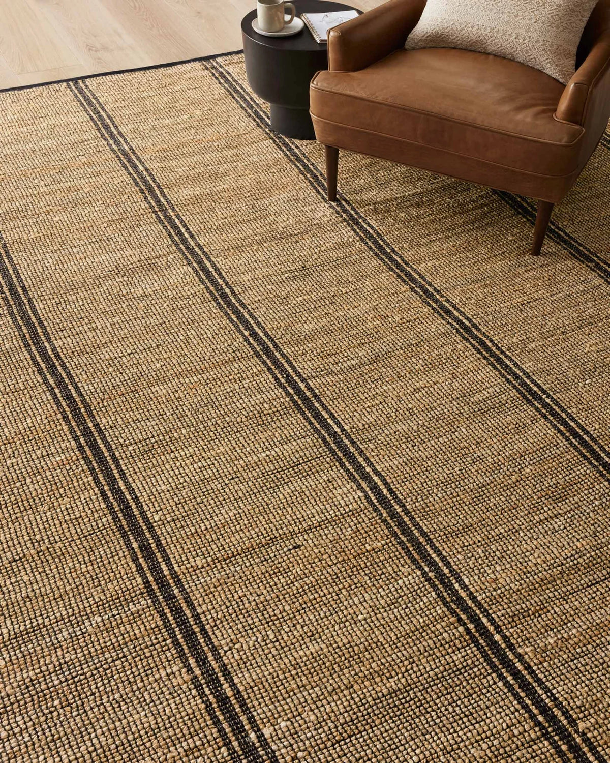 Colton handwoven area rug in Natural and Black featuring a timeless linear pattern crafted from a soft jute and cotton blend.