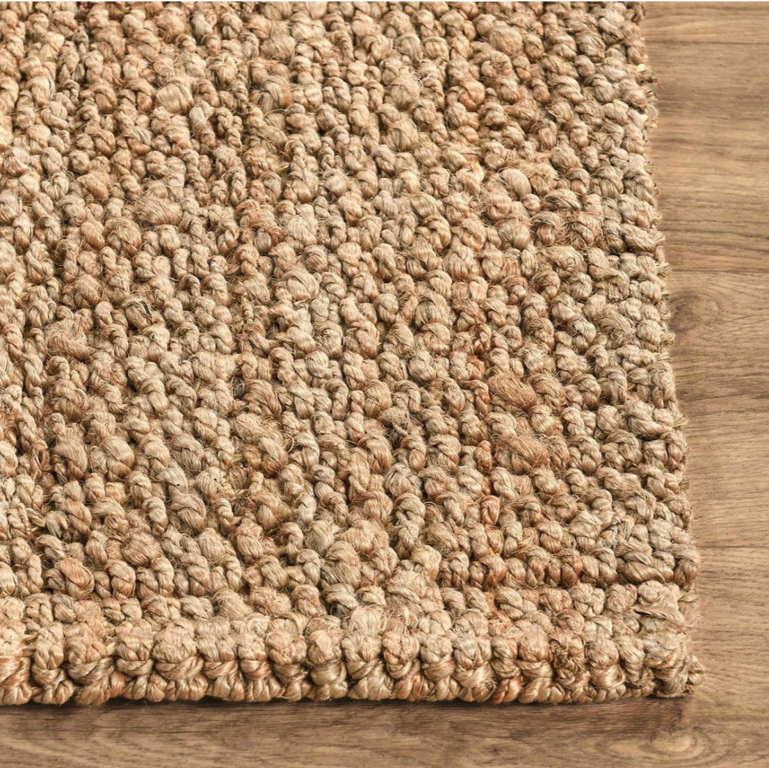 Close-up of a textured beige rug on a wooden floor
