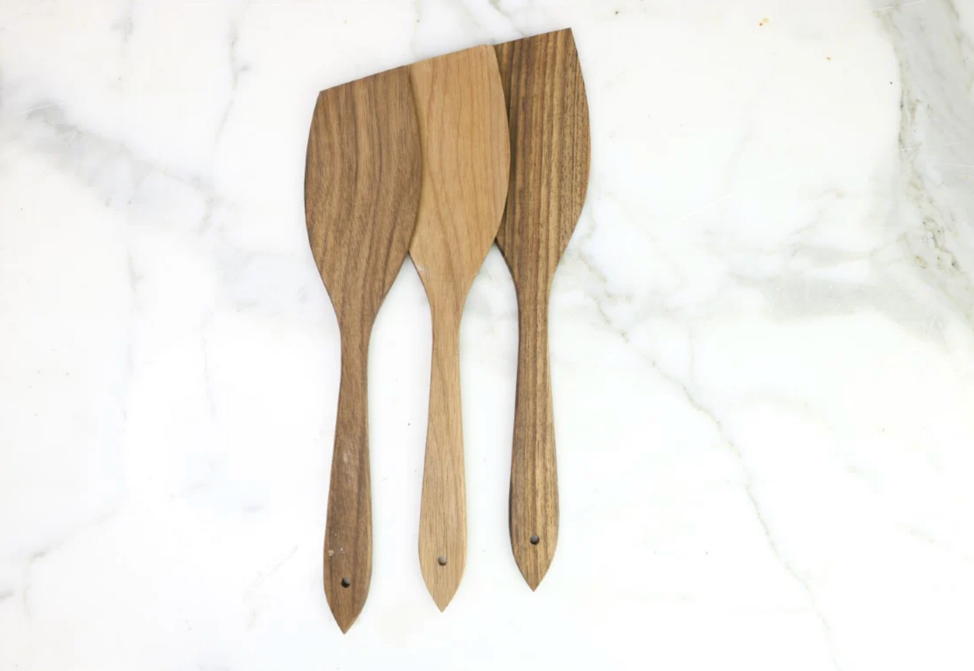 Three wooden spatulas on a white marble surface