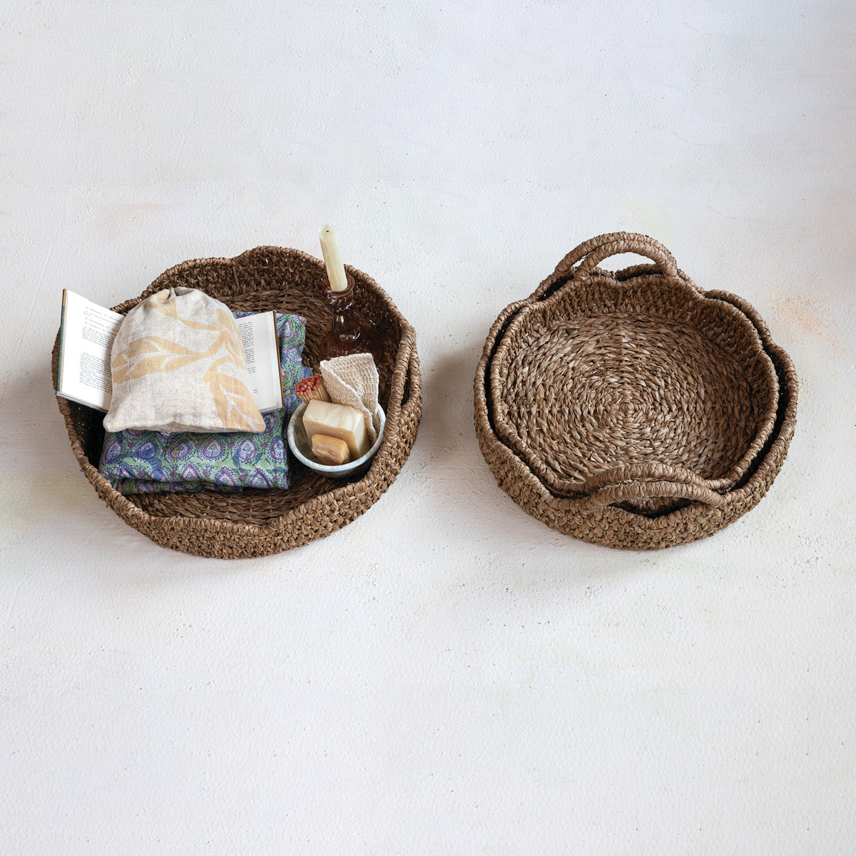 Three sizes of natural braided bankuan and rattan trays with scalloped edges and integrated handles.