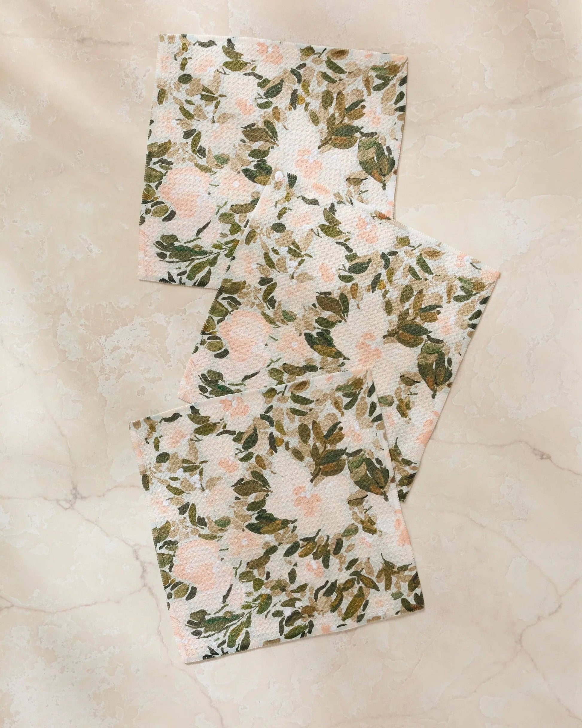 Two floral-patterned towels on a textured beige surface