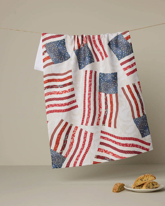 Tea towel with American flag pattern hanging on a line, with cookies on a plate below.