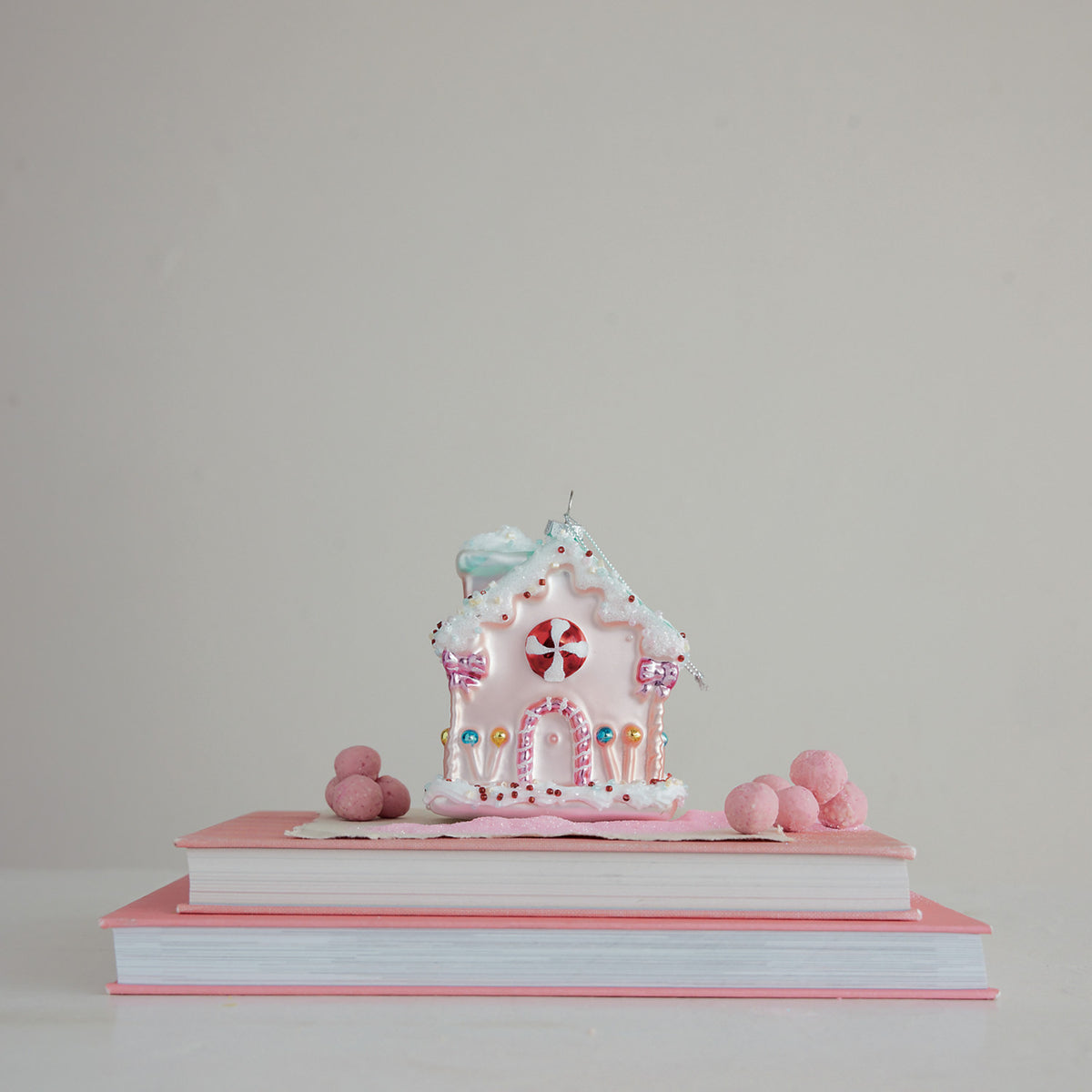 Hand-painted glass candy house Christmas ornament in pink with colorful candy details, glitter, and decorative beads.
