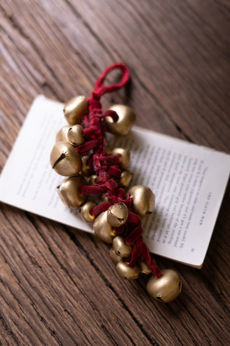 Cluster of metallic jingle bells tied with a rich red velvet ribbon for classic Christmas decorating.
