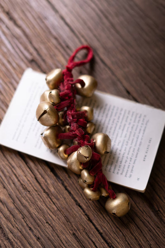 Cluster of metallic jingle bells tied with a rich red velvet ribbon for classic Christmas decorating.