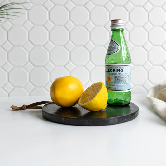 Black marble serving board arranged with lemons and sparkling water for entertaining.
