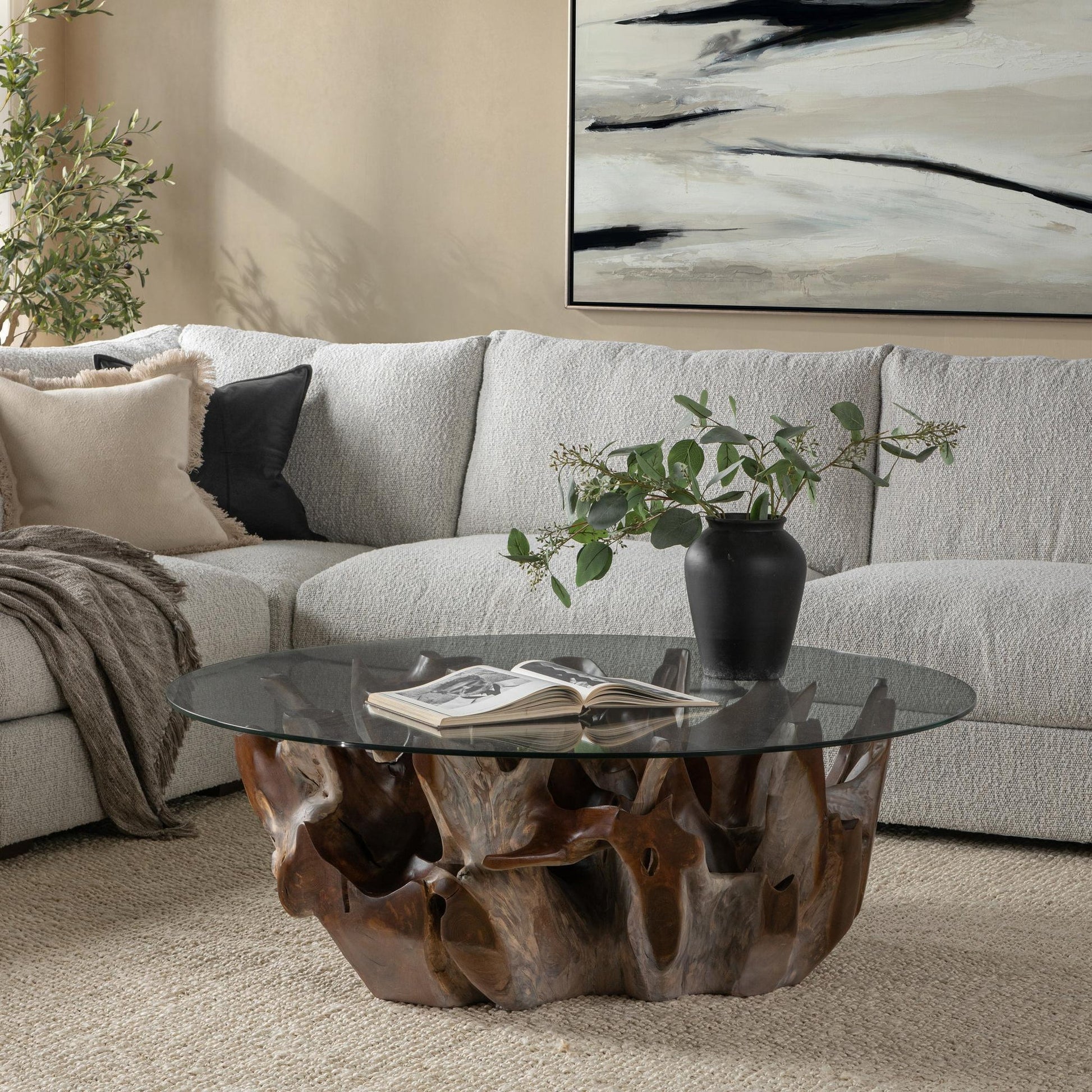 Hailey teak root and glass coffee table styled in an organic modern living room with linen seating, leather accents, and warm wood furnishings.