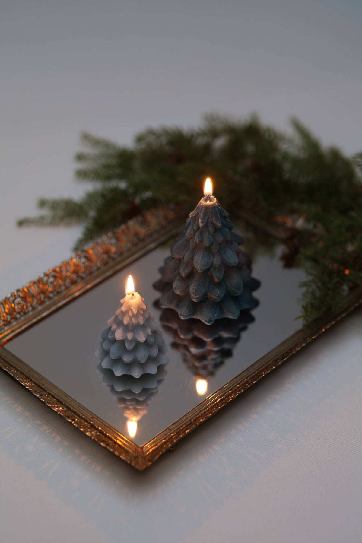Sculpted beeswax Christmas tree candles arranged among collected holiday decorations on a festive mantel or tabletop.