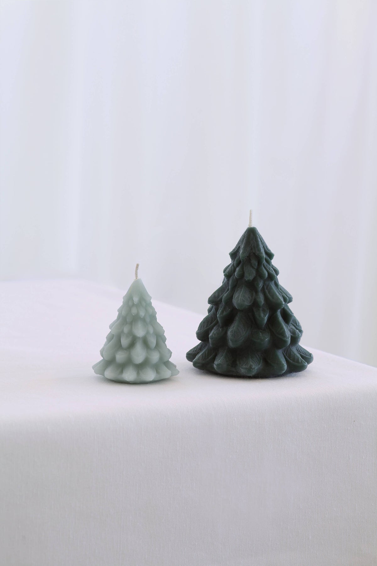 Small and Large Mo&Co Home sculpted beeswax tree candles displayed together to show their coordinating sizes.
