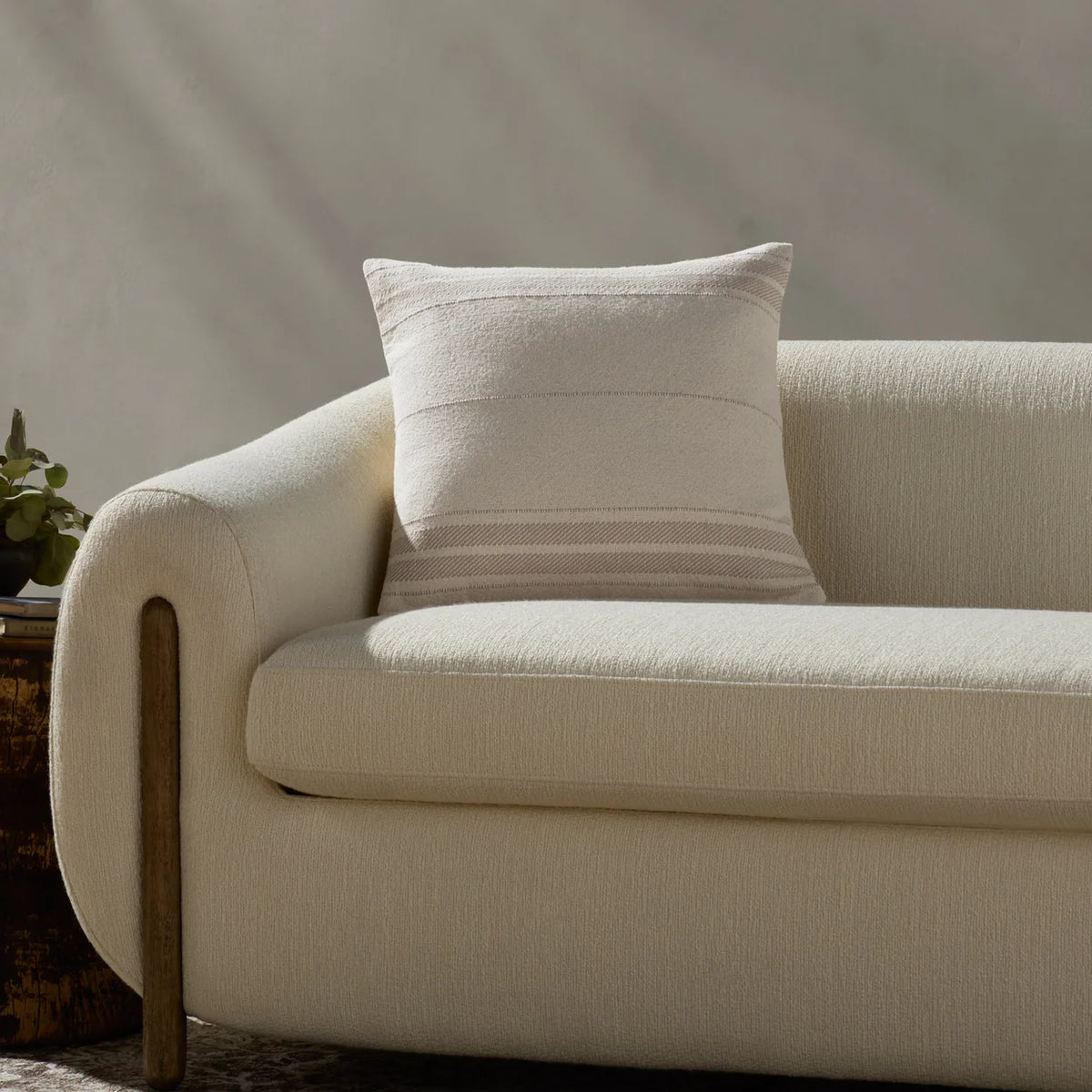 Selena Ivory and Natural throw pillow layered on a linen sofa with warm wood furniture, wool textiles, and handcrafted pottery in an organic modern living room.