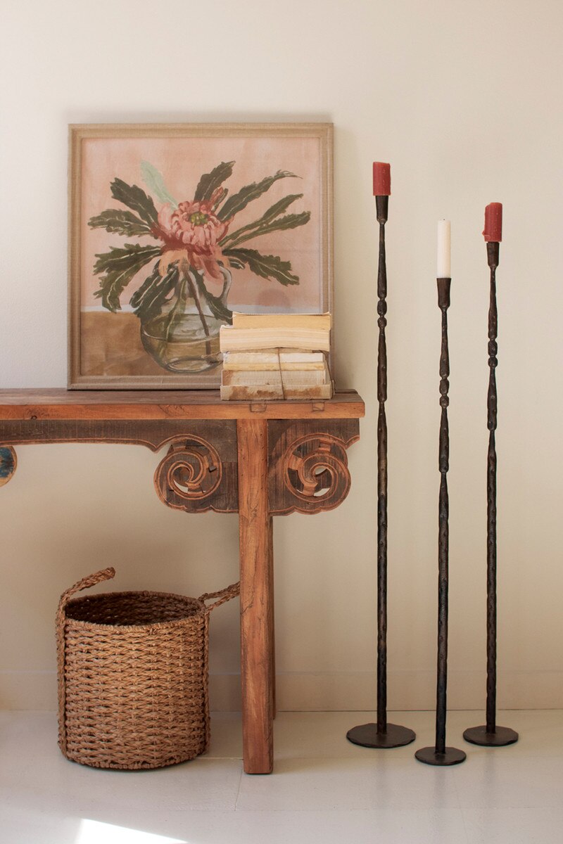Set of three tall forged iron taper candle holders with an antique brass finish.