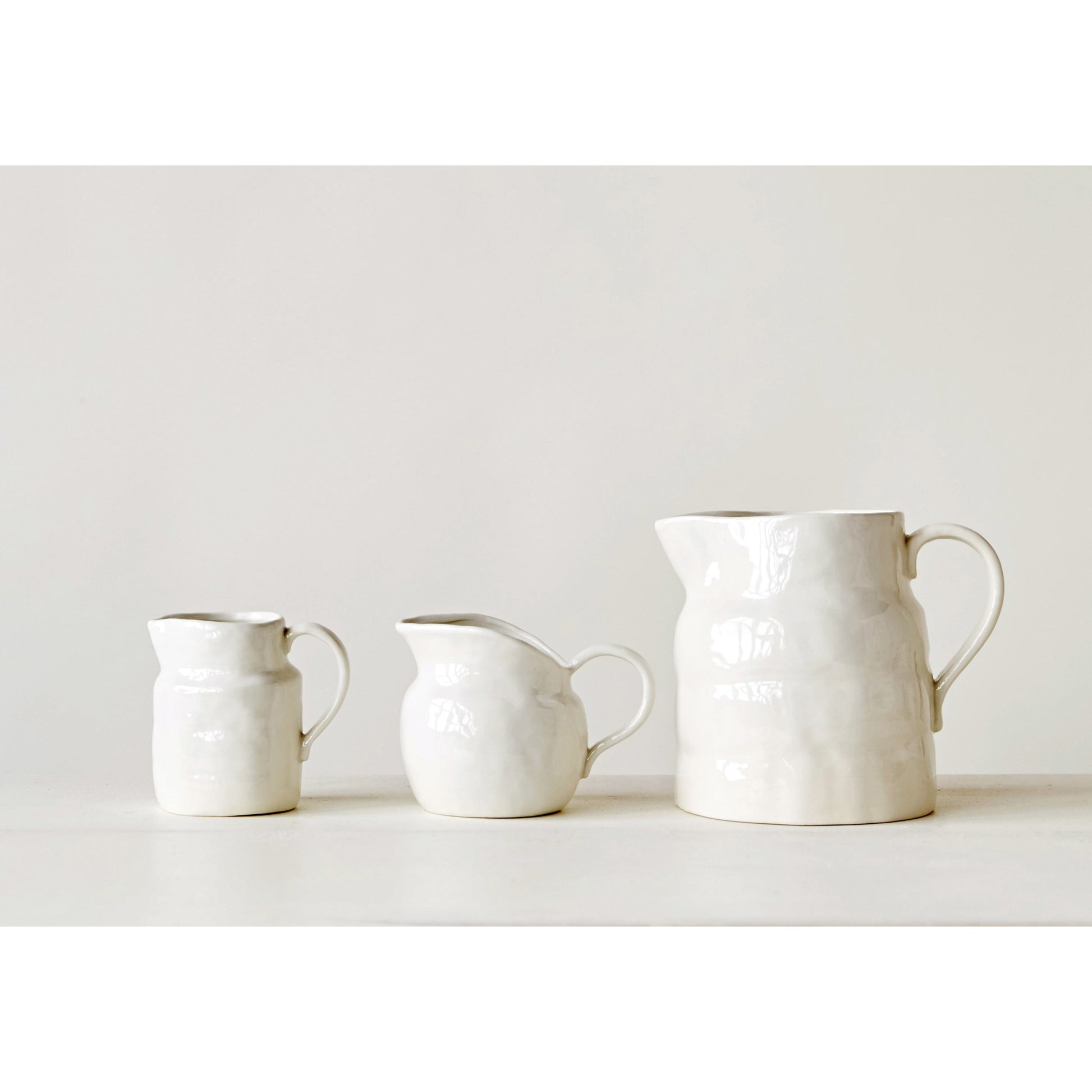 Small stoneware pitcher serving cream and juice on a thoughtfully styled breakfast table.