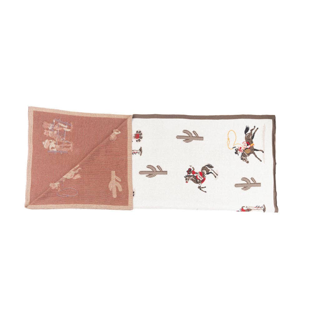 Woven cotton throw blanket featuring classic cowboy scenes and Southwestern-inspired patterns in burgundy, cream, black, and brown.