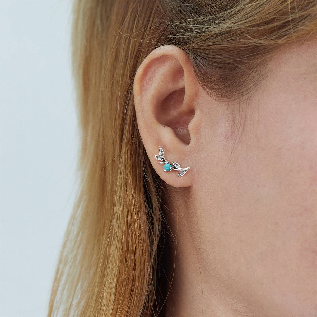 Botanical-inspired sterling silver leaf earrings featuring a natural stone accent.