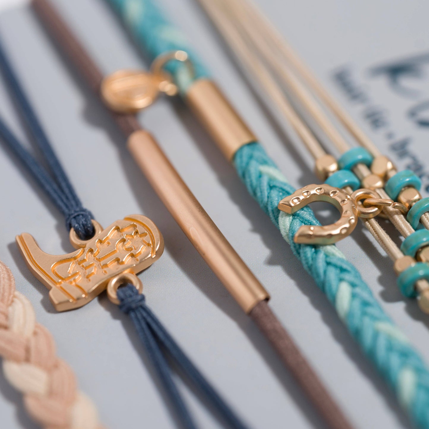 Close-up of Stride Western hair tie bracelets featuring gold-tone beads, cowboy boot charm, horseshoe charm, and turquoise-inspired colors.