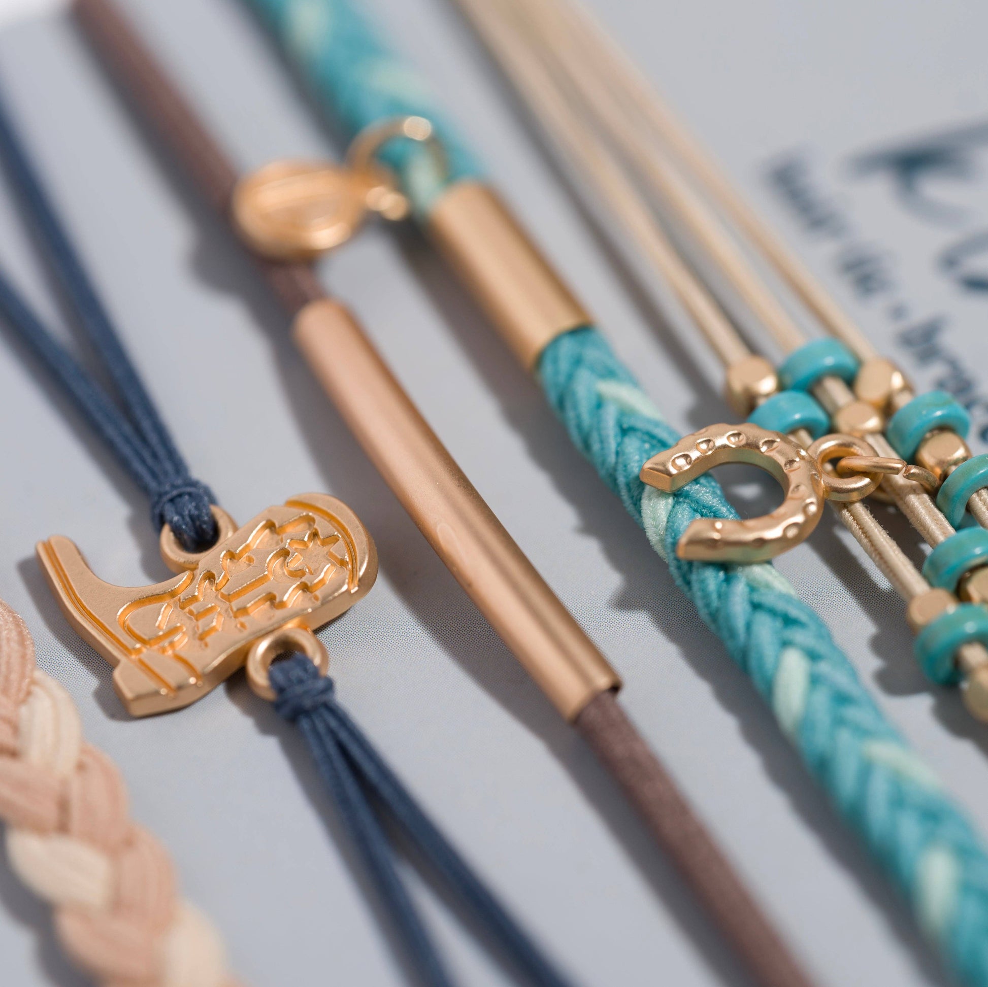Close-up of Stride Western hair tie bracelets featuring gold-tone beads, cowboy boot charm, horseshoe charm, and turquoise-inspired colors.
