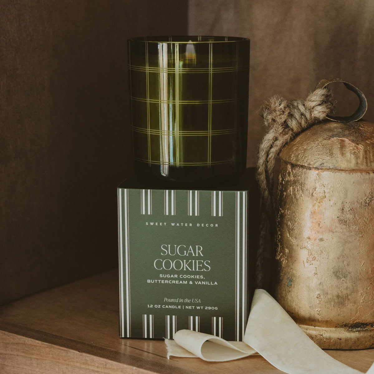 Sugar Cookies 12 oz soy blend candle in a translucent olive green glass vessel with festive plaid detailing.