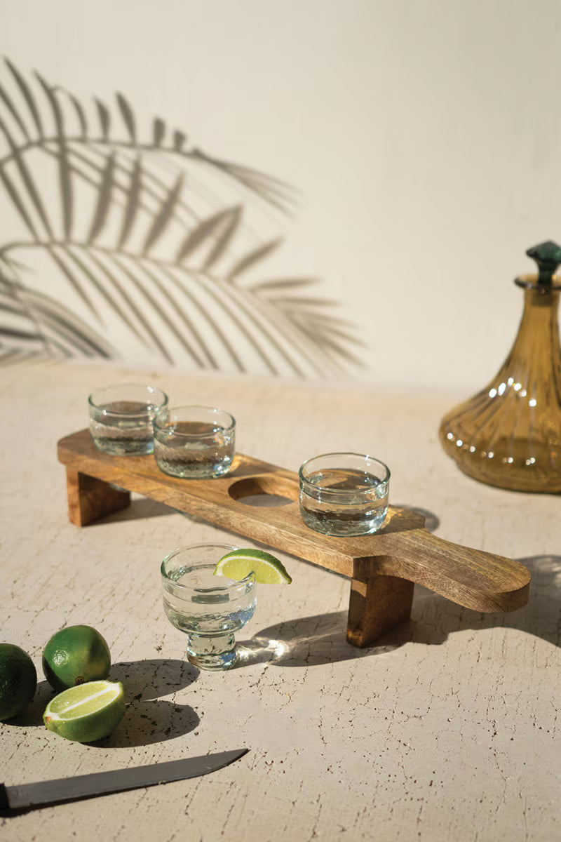 Tequila flight serving set with four tasting glasses on a wooden tray.