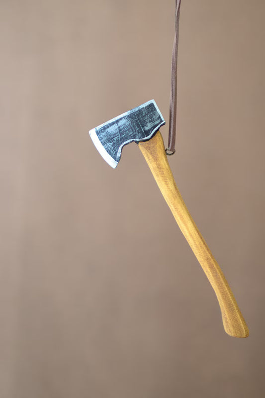 Vintage-inspired axe Christmas ornament crafted from wood, metal, and faux suede with a distressed finish.
