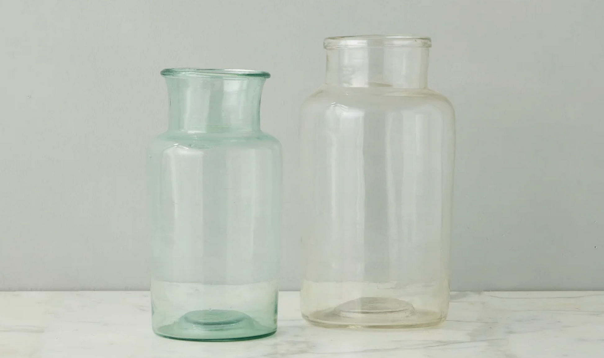 Two glass jars on a white surface with a light gray background