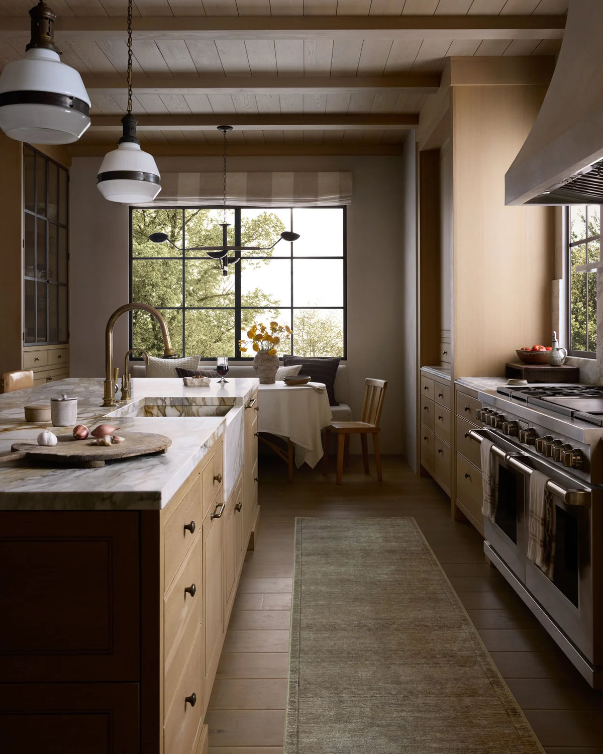 Modern kitchen with wooden cabinets, marble countertops, and large windows.